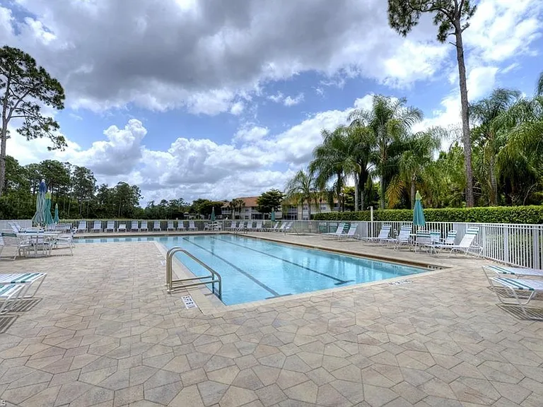 Community Pool & Hot Tub _ Enjoy a resort-style heated pool and relaxing hot tub, surrounded by lush tropical landscaping and ample lounge seating. The spacious sun deck offers plenty of room for sunbathing, reading, or unwinding under shaded umbrellas.