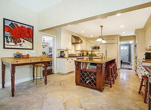 Stunning kitchen features custom cabinetry, granite countertops, tumbled marble backsplash with a pr
