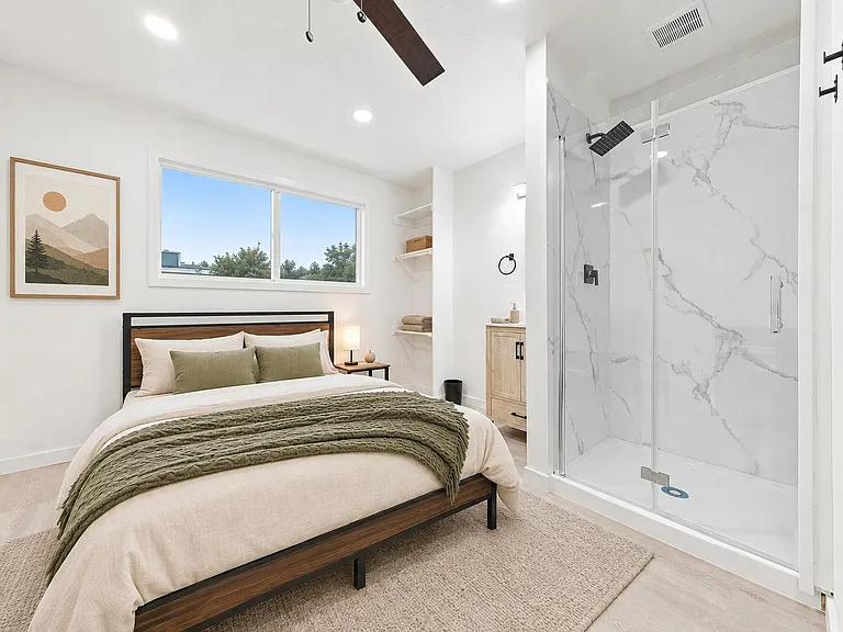Private bedroom with large window, ceiling fan, and convenient ensuite-style walk-in shower plus open shelving.