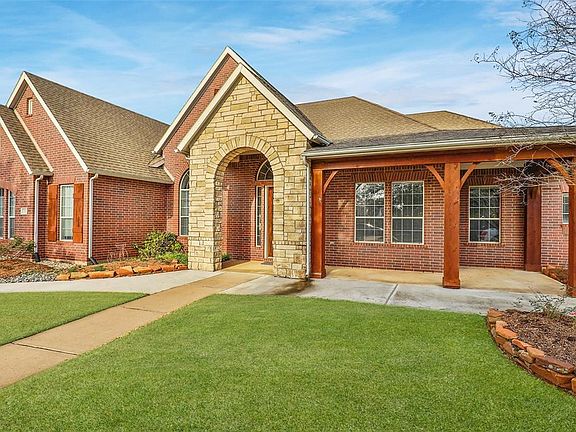 This David Weekley home in Lakes of Fairhaven features a front porch exterior with expanded paving and a stone entryway.