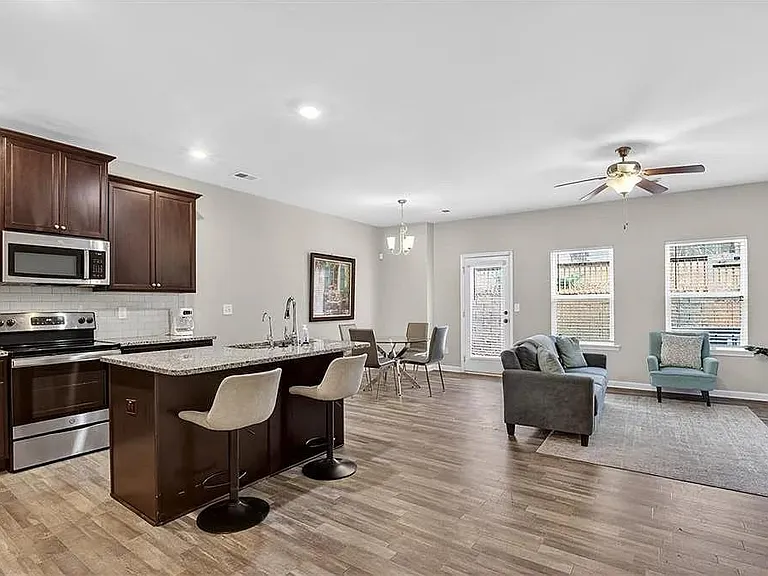 Open-concept living area with kitchen island seating, stainless appliances, and space for dining and lounging.