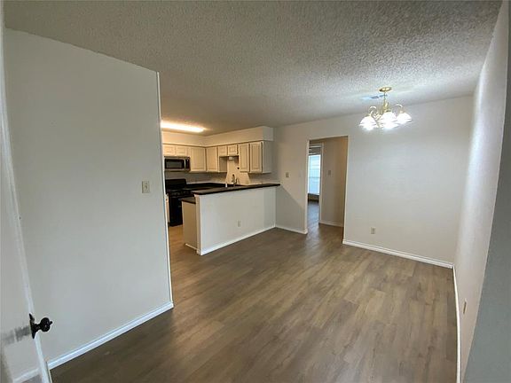 Kitchen with stainless steel microwave, a notable chandelier, gas stove, and dark wood finished floors