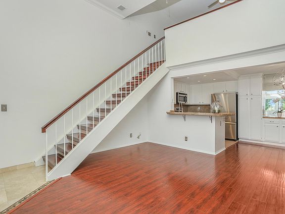 Spacious living room with high ceilings, natural light and engineered wood flooring.