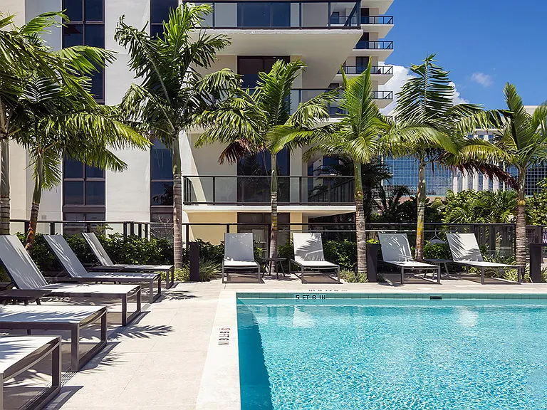 Griffis West Palm apartments rooftop pool area with lounge chairs and palm trees.