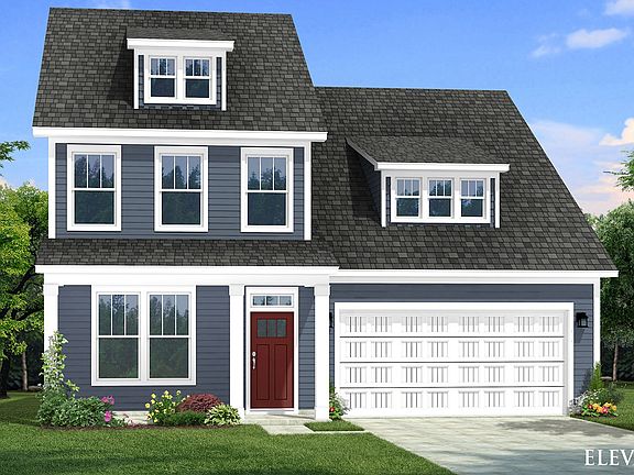 Two-story single family home with blue siding, lots of windows, a covered front porch and 2 car gara