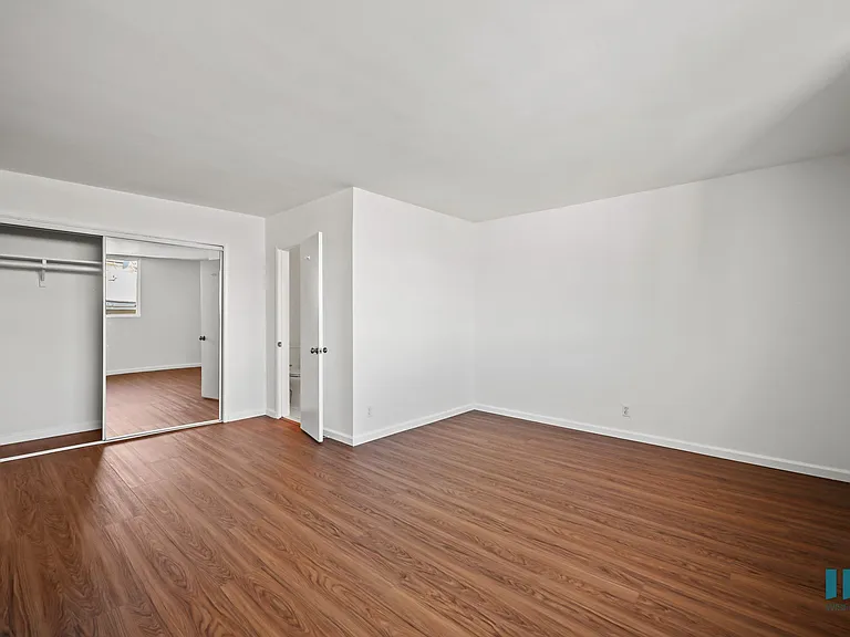 Large-Size Bedroom with a Mirrored Closet and Hardwood Flooring