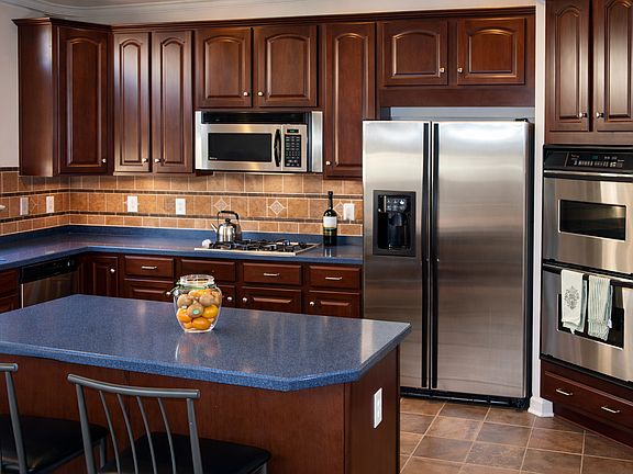 A refined and thoughtfully designed kitchen, featuring rich wood cabinetry, stainless steel appliances, and an expansive island that balances efficiency with elegance