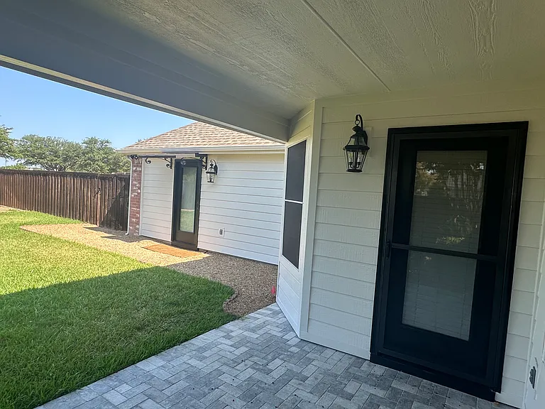 Tiled covered patio and lighting
Pea gravel patio, canopy, sconce and security motion sensor lighting for garage entry door.
