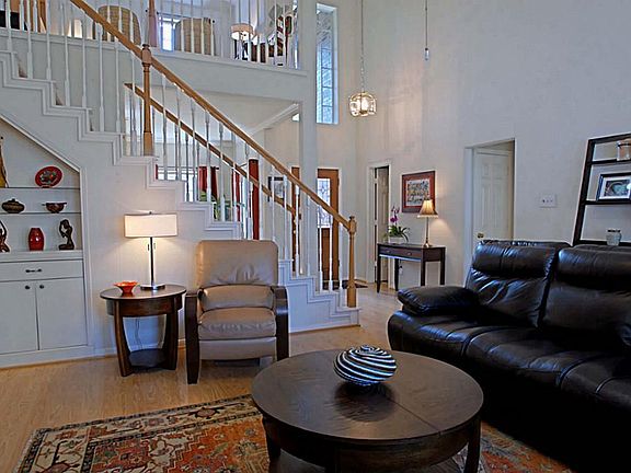 View from the living room looking back toward the sunlit entry and second floor loft area. Notice th