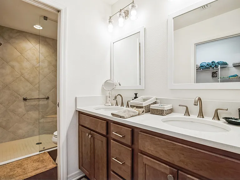 Master Bathroom with Sink and Mirrors for Him and Her, and a Partitioned Area for Toilet and a Tiled Shower.