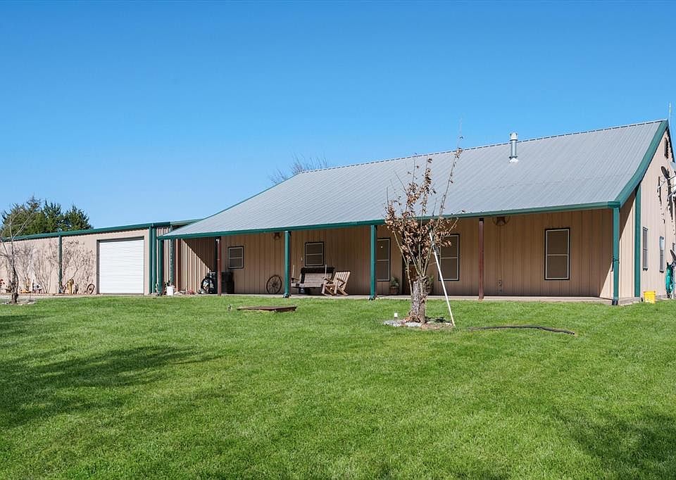 Rear view of house with a lawn, a garage, and a metal roof