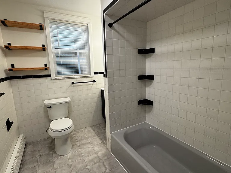 Bathroom (Actual Picture): Updated full bathroom with a tiled tub/shower, refreshed finishes, and convenient open shelving for extra storage
