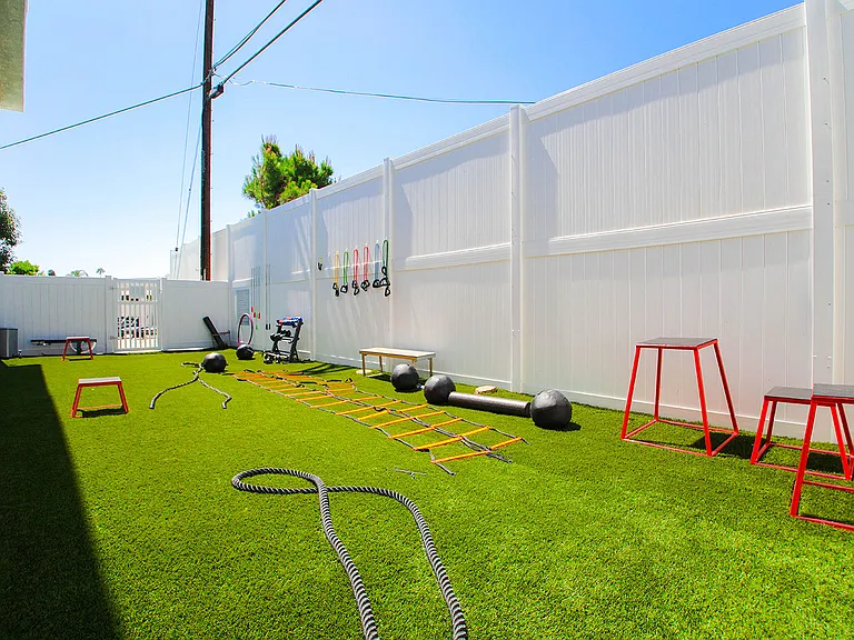 Outdoor fitness center with free weights, jump ropes, and medicine balls.