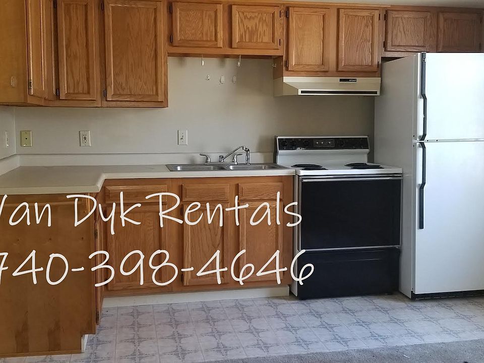 View of kitchen with range and refrigerator plus plentiful cabinets.