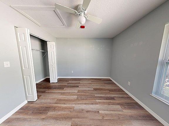 Bright, spacious bedroom with sleek hardwood floors, generous closet space, and abundant natural light from large windows.