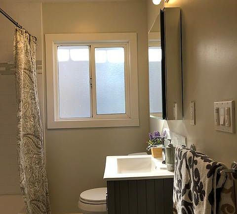 Full size view of the beautifully remodeled bathroom with tub/shower gray maple shaker cabinet, tile flooring, tile flooring and tub/bath surround.