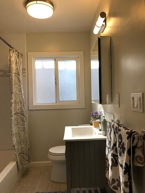 Full size view of the beautifully remodeled bathroom with tub/shower gray maple shaker cabinet, tile flooring, tile flooring and tub/bath surround.