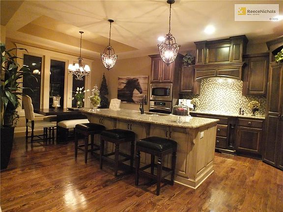 Upgraded kitchen with stainless appliances, granite island and custom wood covering over hood.