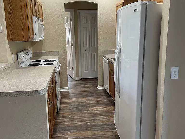 Kitchen view from dining room - with passthrough from sink window to lanai. Dining room with sliding doors to lanai.