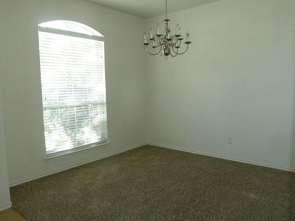 Spare room with a healthy amount of sunlight, a chandelier, and dark colored carpet