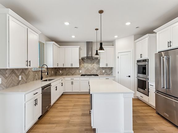 The kitchen has white wood cabinetry with black hardware.