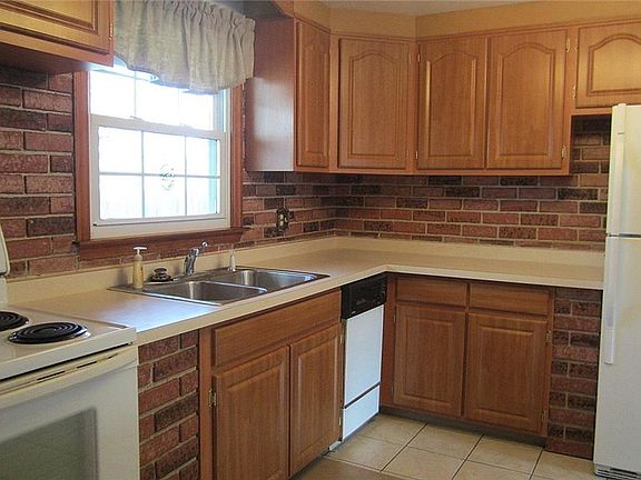 The updated Kitchen features all the appliances, refinished cabinetry, a double stainless steel sink, a ceramic tile floor, and sharp brick backsplash and trim.