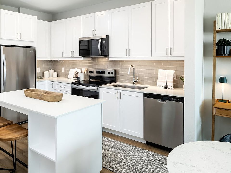 Finish Package I kitchen with stainless steel appliances, white cabinetry, grey tile backsplash, white quartz countertops, and hard surface flooring
