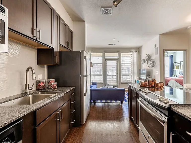 Classic Package kitchen with espresso cabinetry, speckled granite countertops, grey subway tile backsplash, stainless steel appliances, and hard surface flooring