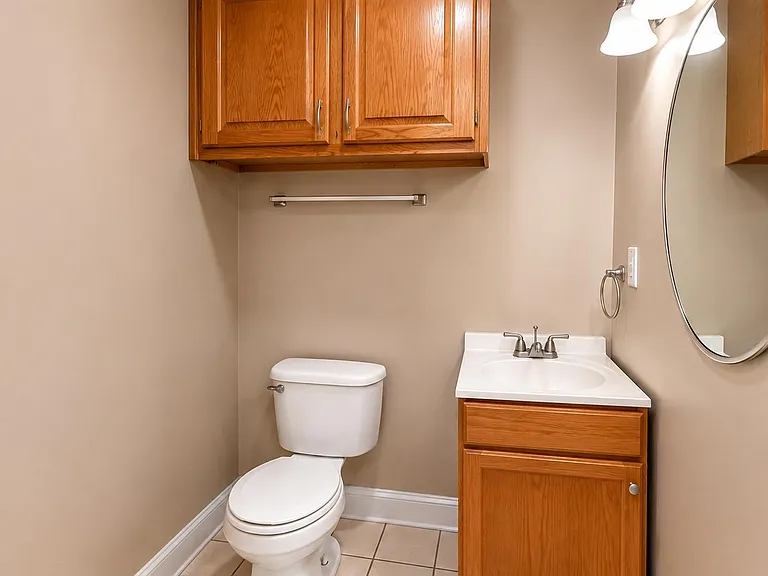 Half bath with vanity storage, overhead cabinetry, and a large wall mirror for easy daily routines.
