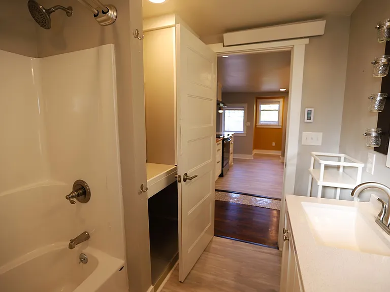 View from bathroom back towards hallway. Large closet / storage area located behind tub/door.
