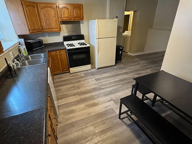 Functional kitchen with ample cabinet storage, double-basin sink, gas range, and full-size refrigerator plus dining nook.