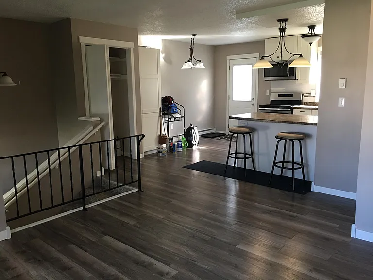 View from upstairs living area, into kitchen. The door opens onto a large, shared deck.
