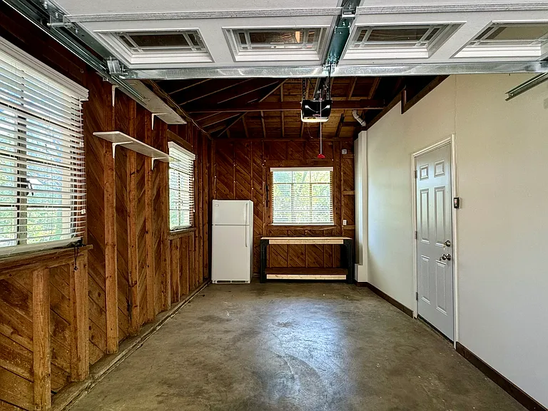 Recently renovated single-car garage with full-size refrigerator and work table.