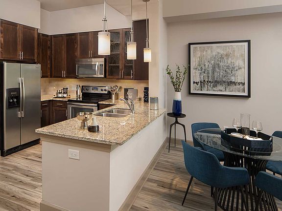Kitchen with stainless steel appliances, dining area with table, granite counters and double basin sink