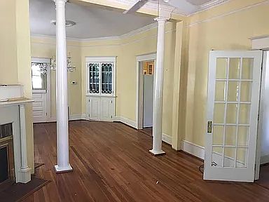 Living rooms and doorway to kitchen on right through columns