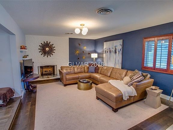 Front entry into sunken Formal Living Room with gas fireplace and hearth, ceiling light fixture, beautiful warm tone laminate fl
