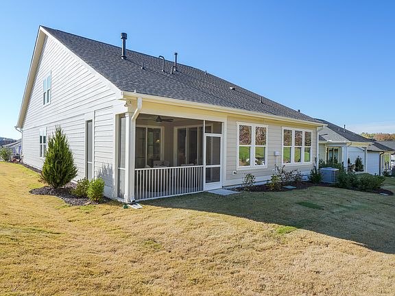 A two-story white house with a porch and a well-manicured lawn in the foreground, set against a clea