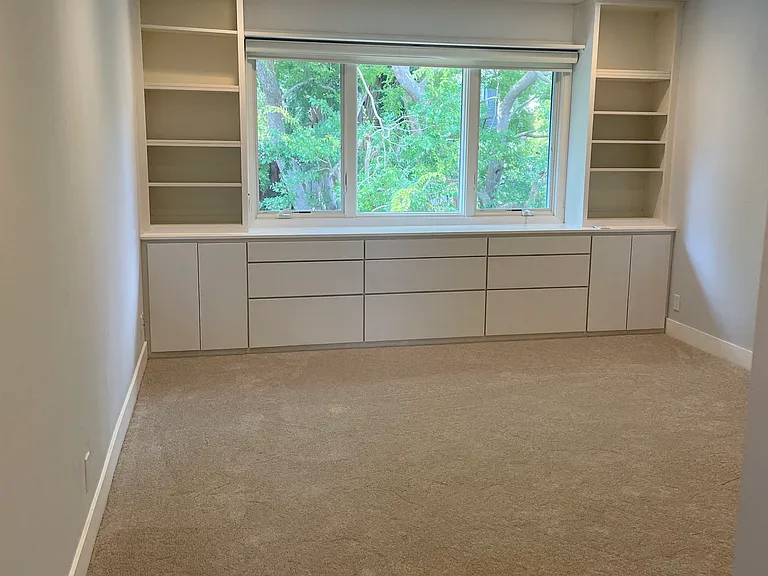 Primary bedroom with built ins and view of the backyard