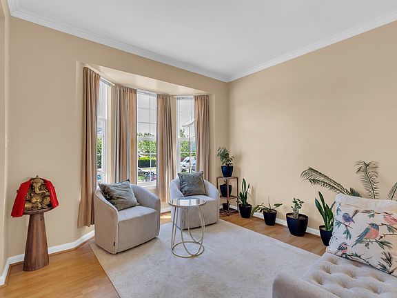 Sunlit front room with bay window, crown molding, and hardwood floors