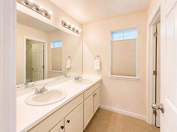 Shared upstairs bathroom with dual sinks, large vanity and generous cabinet storage. Shared with up to two other residents. Digitally enhanced for presentation.