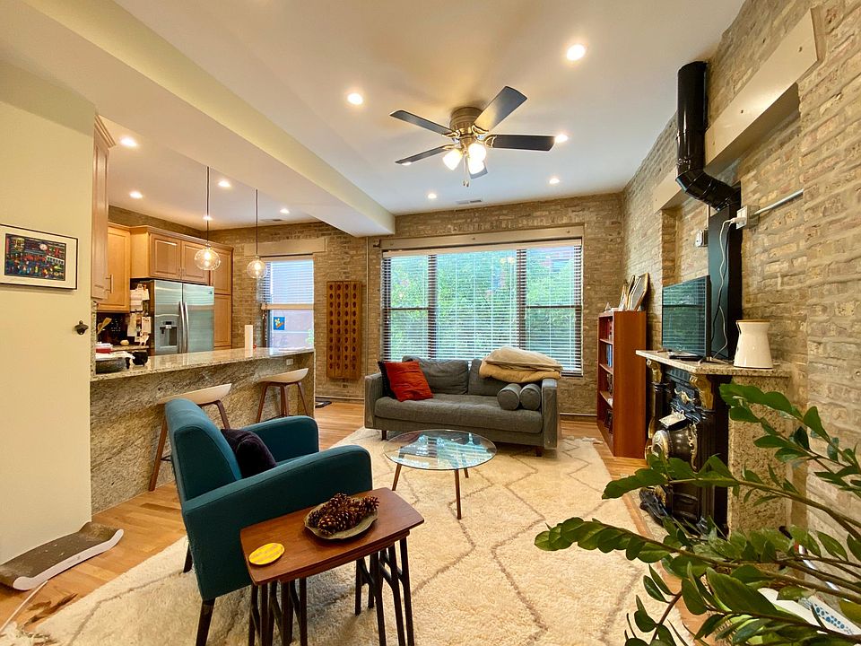 open concept living/kitchen with exposed brick and large windows