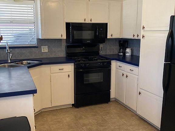 Gas range and built in microwave. Kitchen features large storage cabinets.
