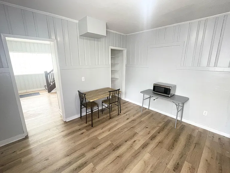 Eat-in dining nook with table seating, built-in shelving, and durable wood-look floors with easy flow to the hallway.