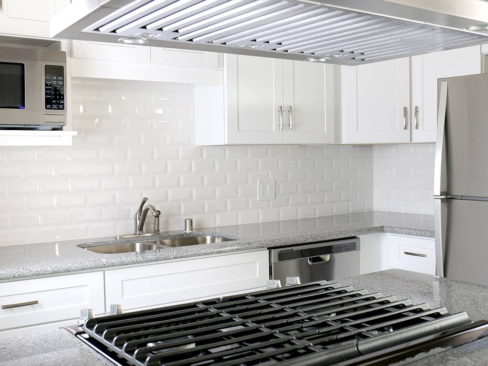 Kitchen with gas range, microwave, dishwasher, and refrigerator at Harbor Villa Apartments in San Diego, California.