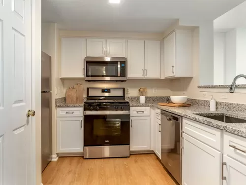 Renovated Package I kitchen with white cabinetry, granite countertops, stainless steel appliances, and hard surface flooring - Avalon Courthouse Place