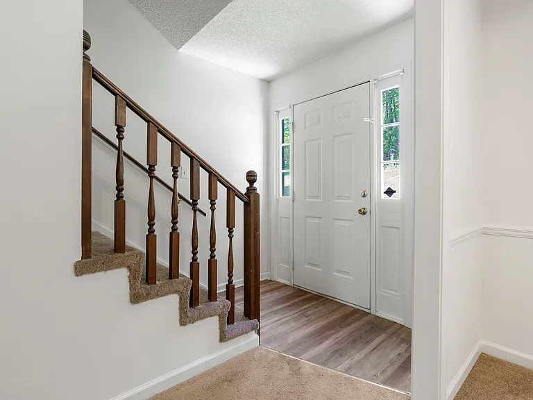 Bright, welcoming foyer with fresh paint, new flooring, and natural light from the double-sidelight entry