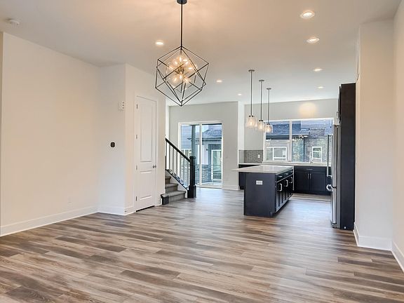 View of dining room, kitchen, balcony door and stairs from living room