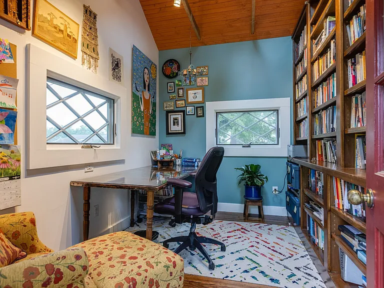 Detached office with built-in bookshelves, fireplace, and colorful character.