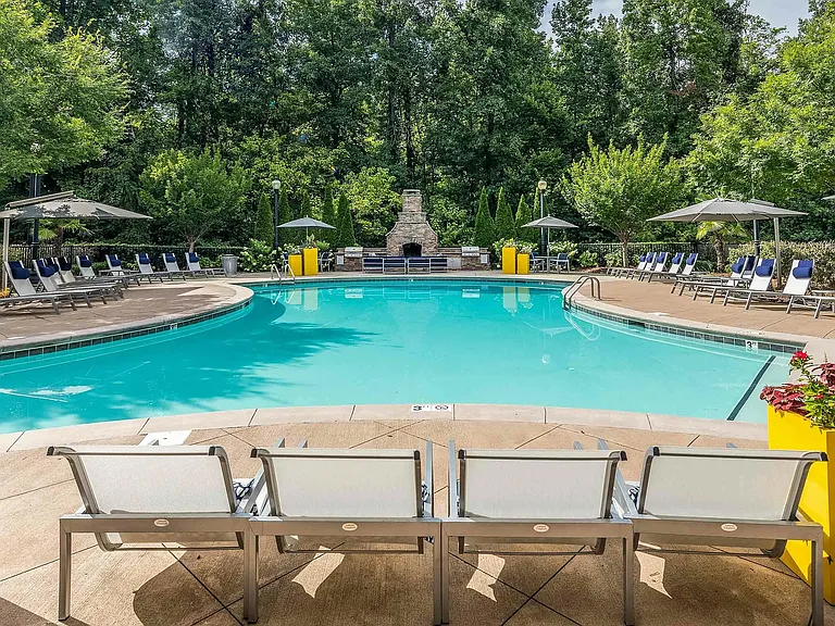 Resort-style swimming pool with spacious sundeck, lounge seating, and outdoor fireplacerelaxing, upscale apartment living in Charlotte