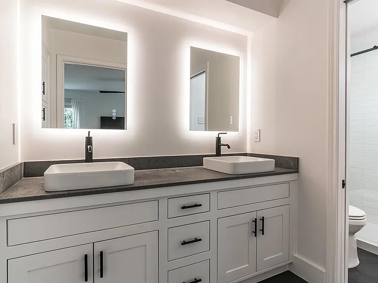 Bedroom #3 Master Bathroom. Completely remodeled featuring adjustable lighting mirrors, cabinetry, black tile flooring, concrete style granite countertops. View to toilet and shower area.